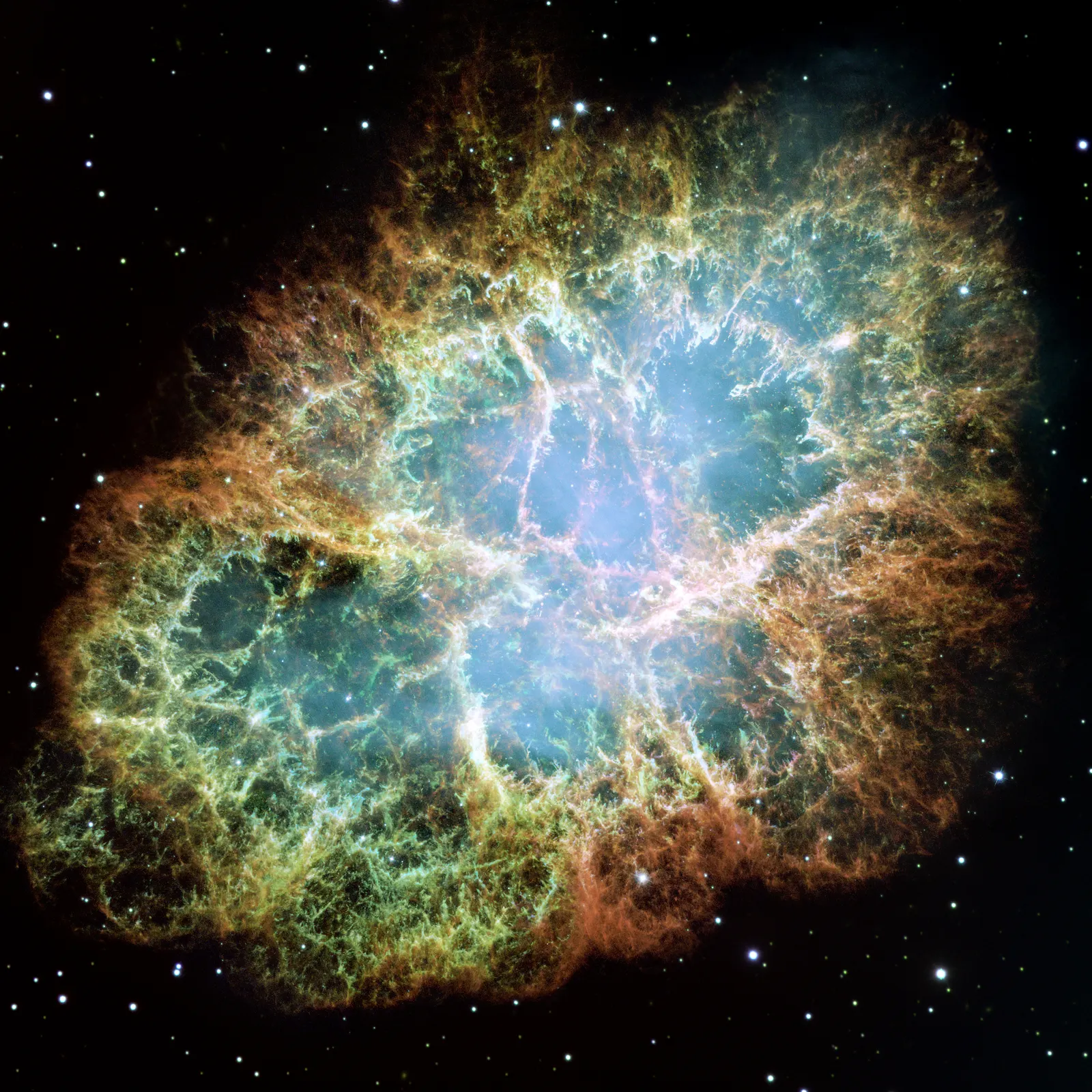 A roughly oval nebula of orange and green filaments around a hazy blue interior, against black space with scattered stars.
