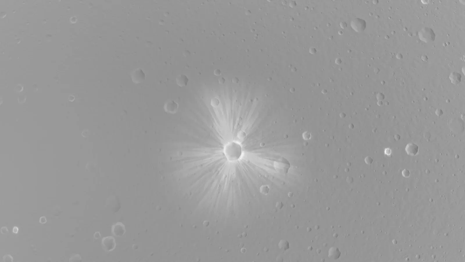 A grey cratered surface seen from above, with a small fresh crater at the centre throwing bright rays outward in every direction.