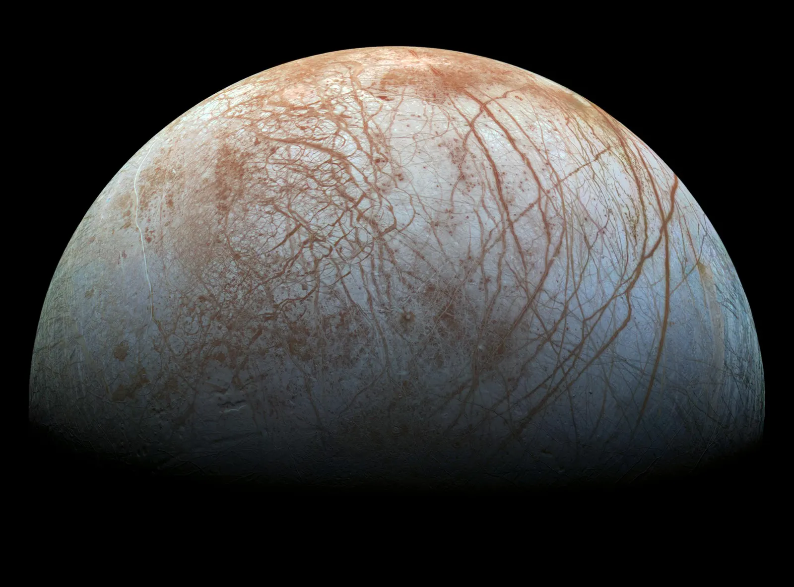 Europa as a pale sphere crossed by long reddish-brown cracks and ridges, bluer toward the poles.