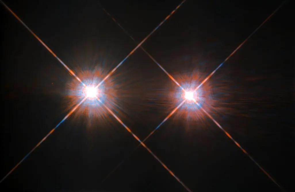 Two bright stars with diffraction spikes close together against a dark sky