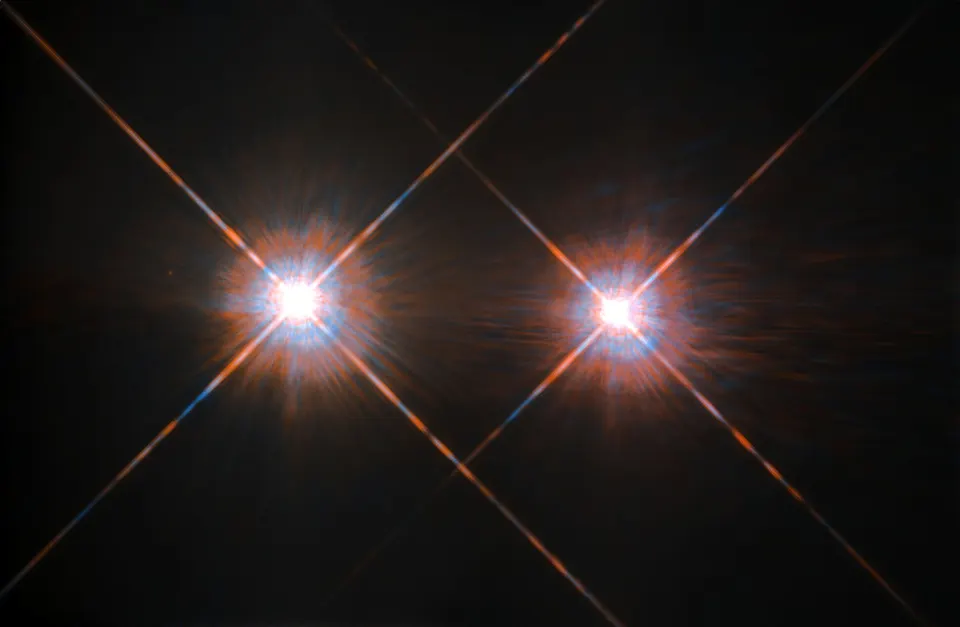 Two bright stars with diffraction spikes close together against a dark sky