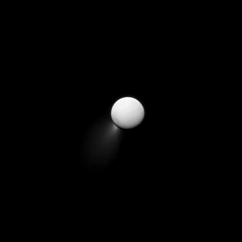 The dark disc of Enceladus lit faintly by Saturn, with a bright fan of ice particles spraying from its south pole.
