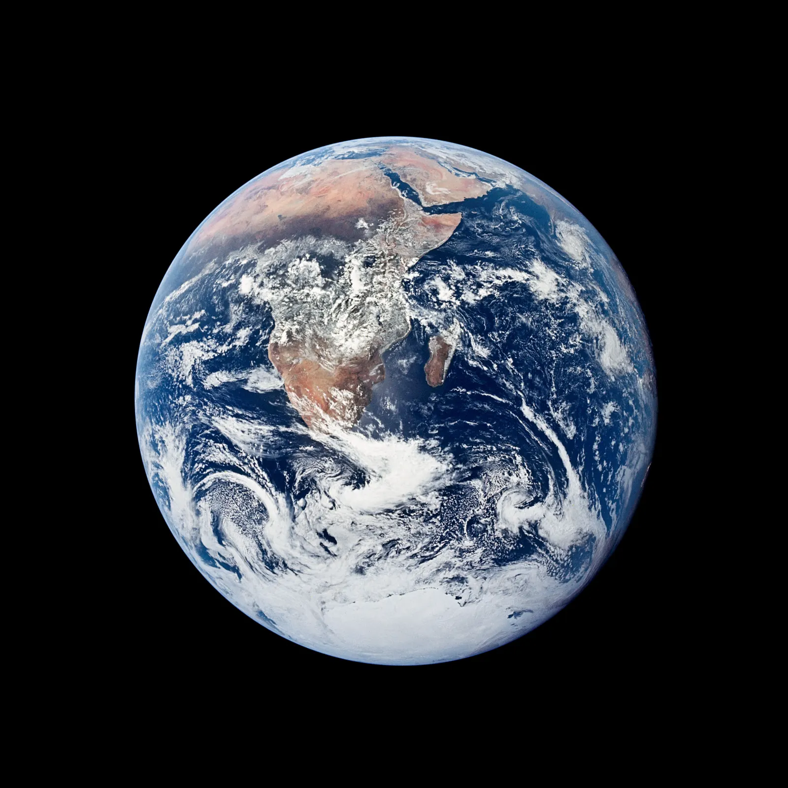 The full Earth seen from space: Africa and Arabia under swirls of white cloud, blue ocean, and the Antarctic ice cap at the bottom.