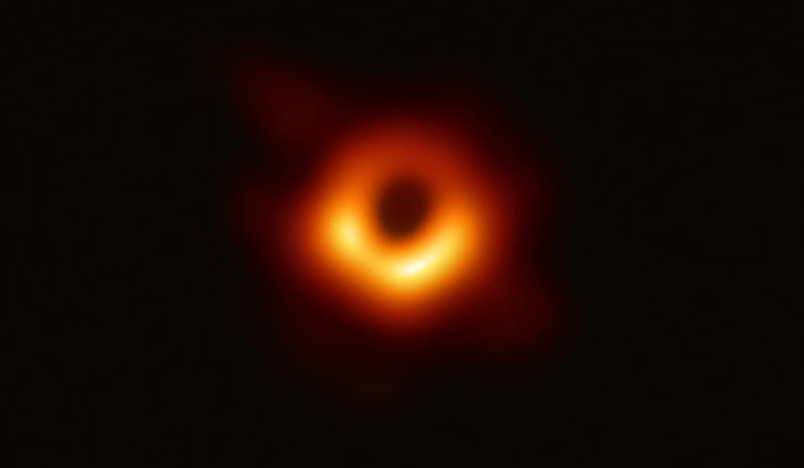 A blurred orange ring, brighter at the bottom, around a dark centre on a black background.