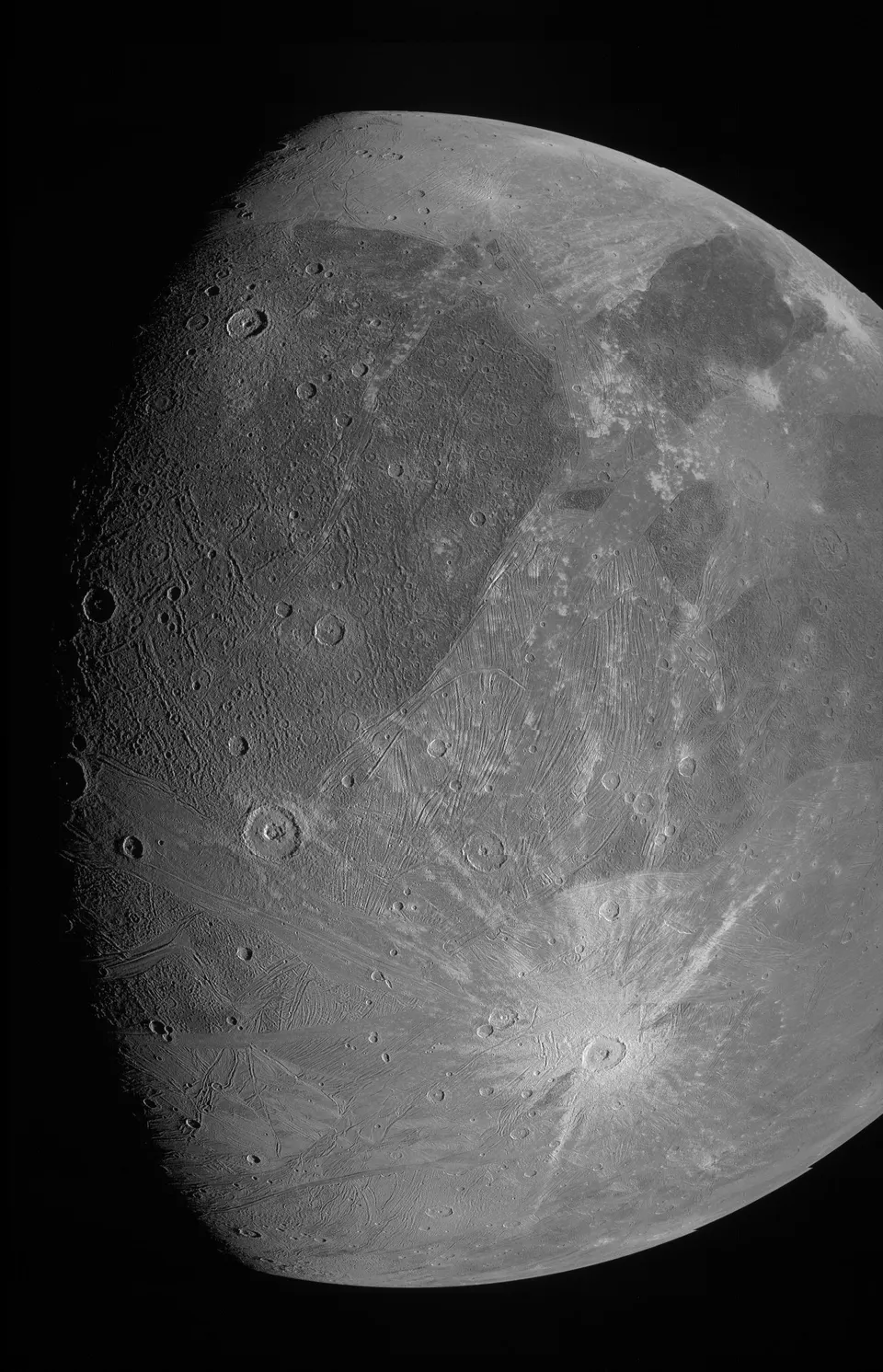 A grey, cratered icy moon with dark and bright terrain and bright rayed craters.